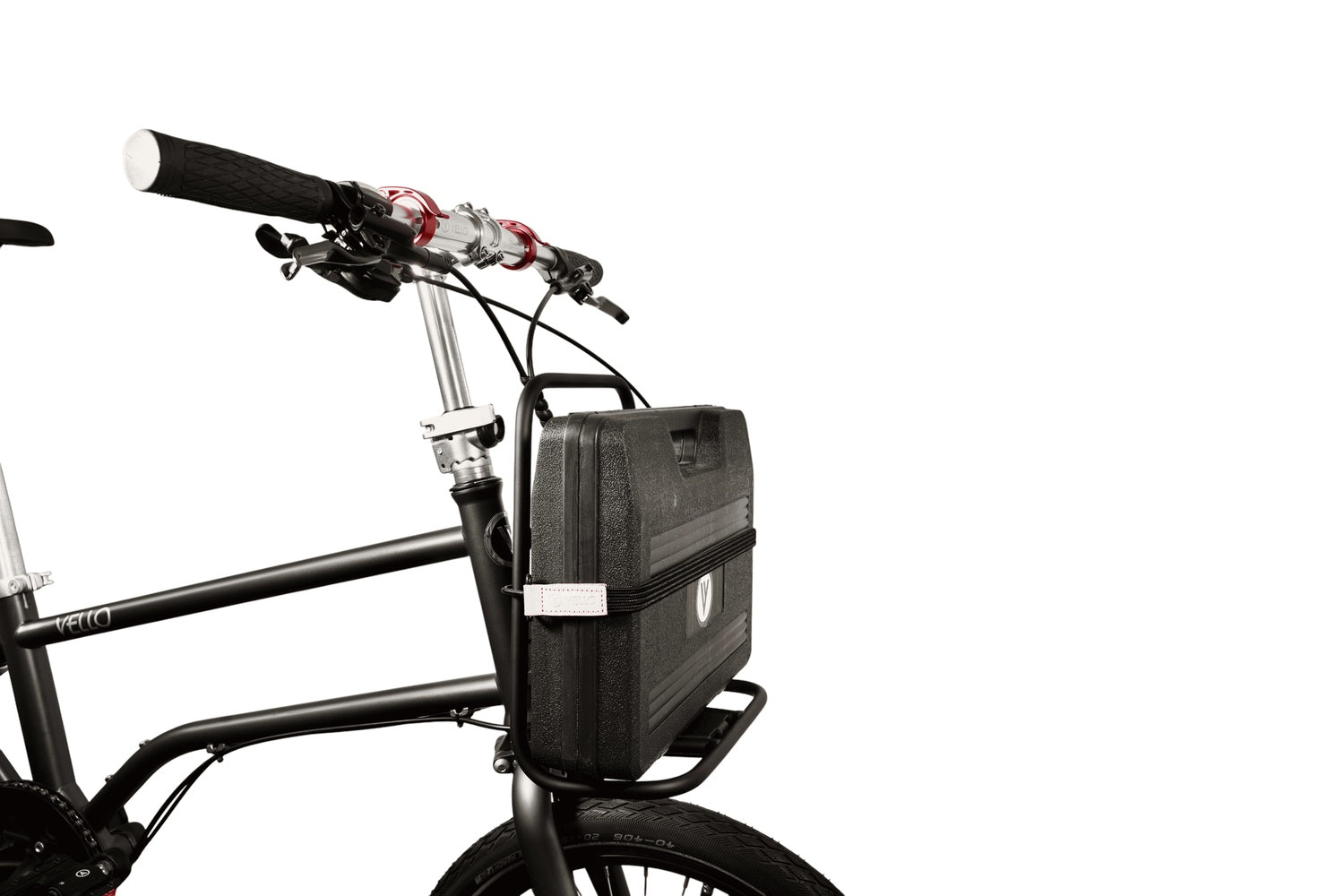 Ein VELLO Faltrad mit "Pizza" Frontgepäckträger der mit einem schwarzen Kunststoffköfferchen beladen ist.