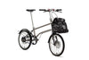 Ein entfaltetes VELLO BIKE plus Automatic Titan Faltrad / Klapprad in der Farbe gebürstetes Titan, mit 20 Zoll Schwalbe Kojak Reifen mit einem Frontgepäckträger in dem eine VELLO Daypack tasche ruht.
