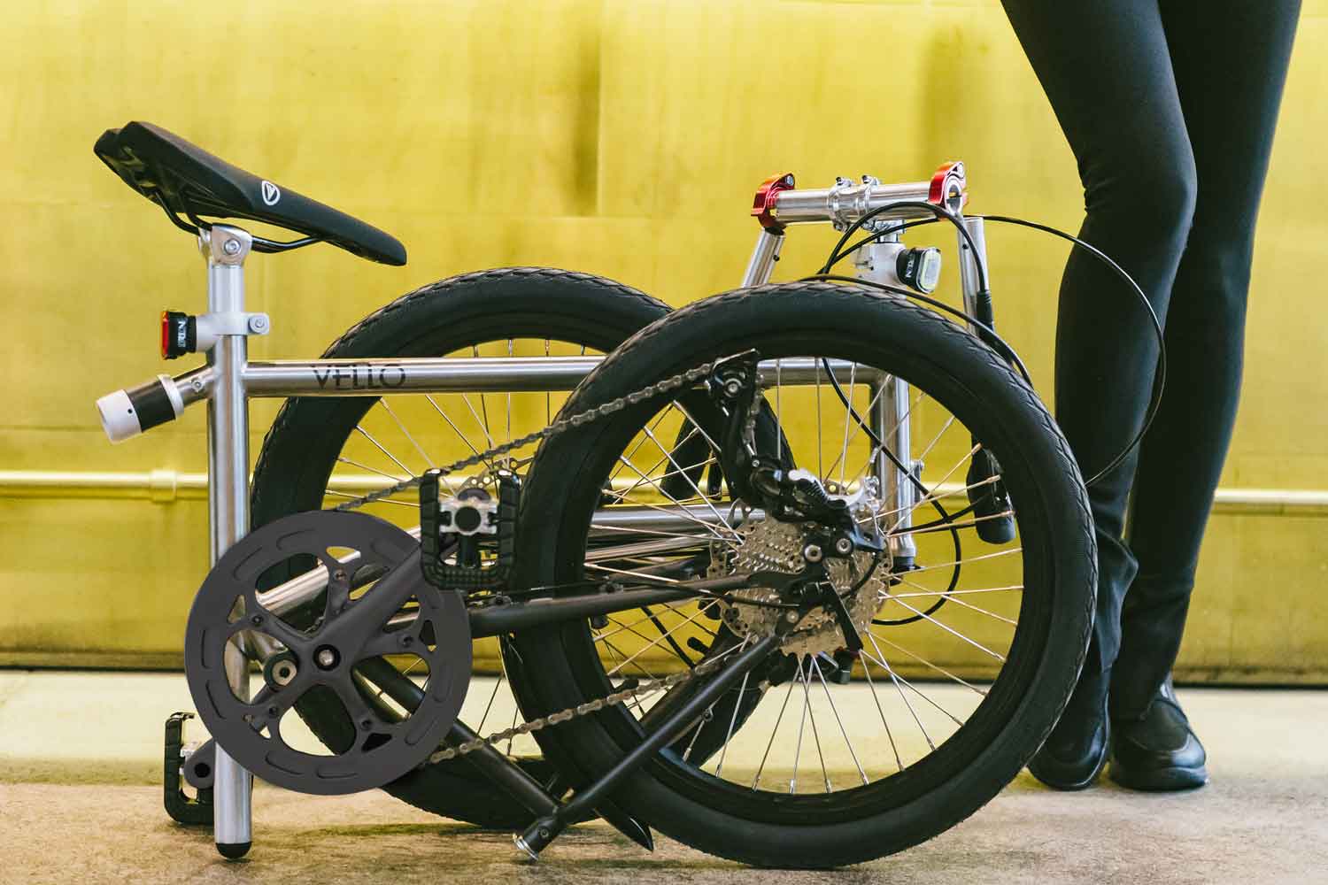 Ein selbst stehendes, gefaltetes VELLO Rocky Titan Faltrad / Klapprad in der Farbe gebürstetes Titan, mit 20 Zoll Schwalbe Kojak Reifen.
