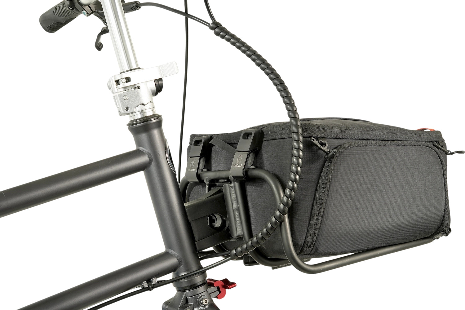 Eine schwarze quadratische Tasche ist mit 2 VELLO HD Spanngurten an einem VELLO Pizza Rack, der wiederum an einem VELLO Faltrad montiert ist, befestigt. Ansicht von seitlich-hinten. 